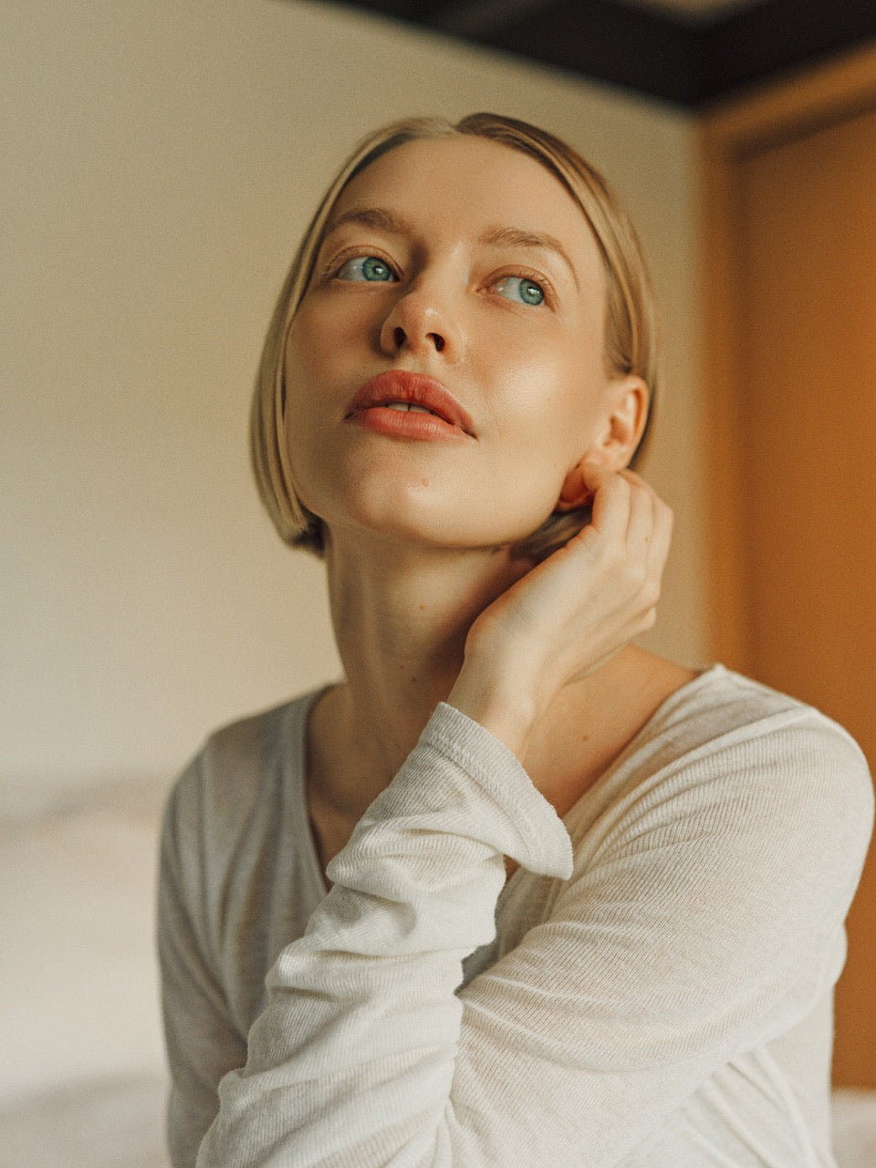 Woman in a white shirt looking upwards with a neutral expression.