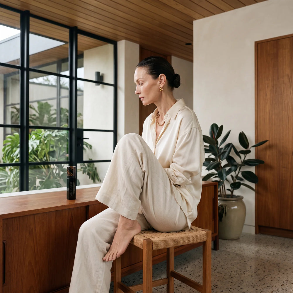 Seated at a teak console by the glazing, the AUTEUR bottle among her own things