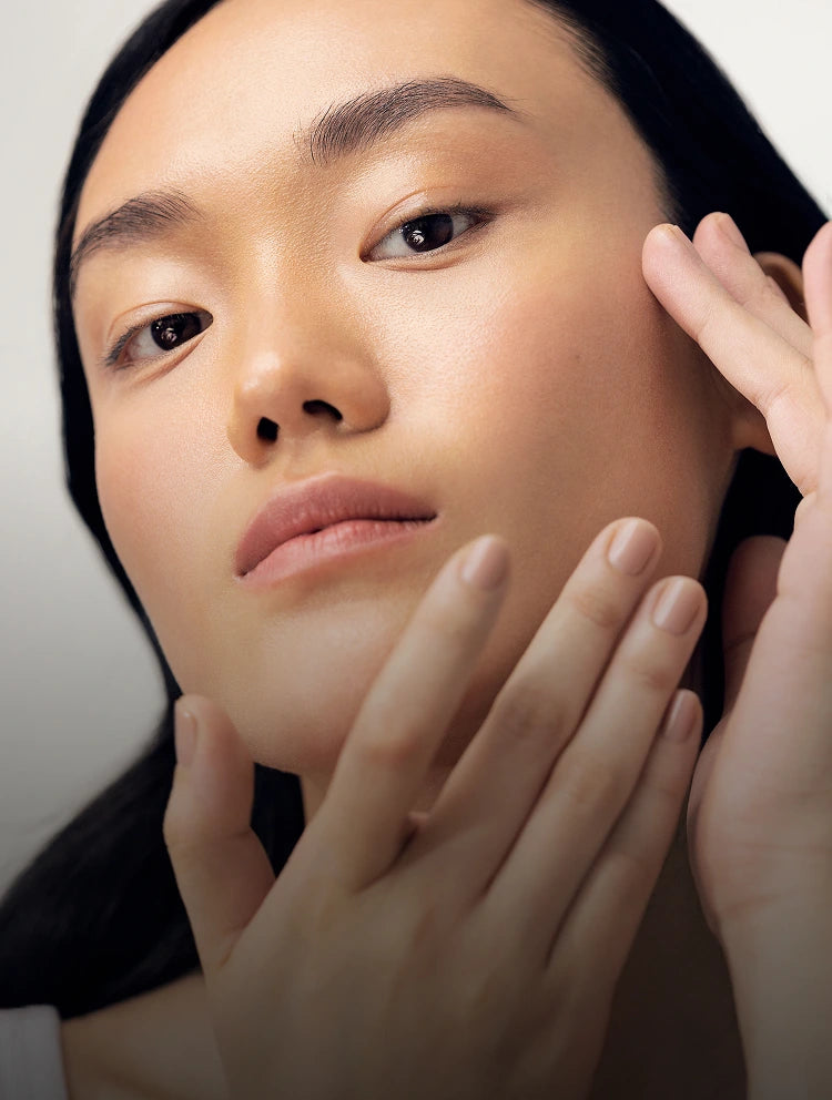 Close-up of a person touching their face with a neutral background