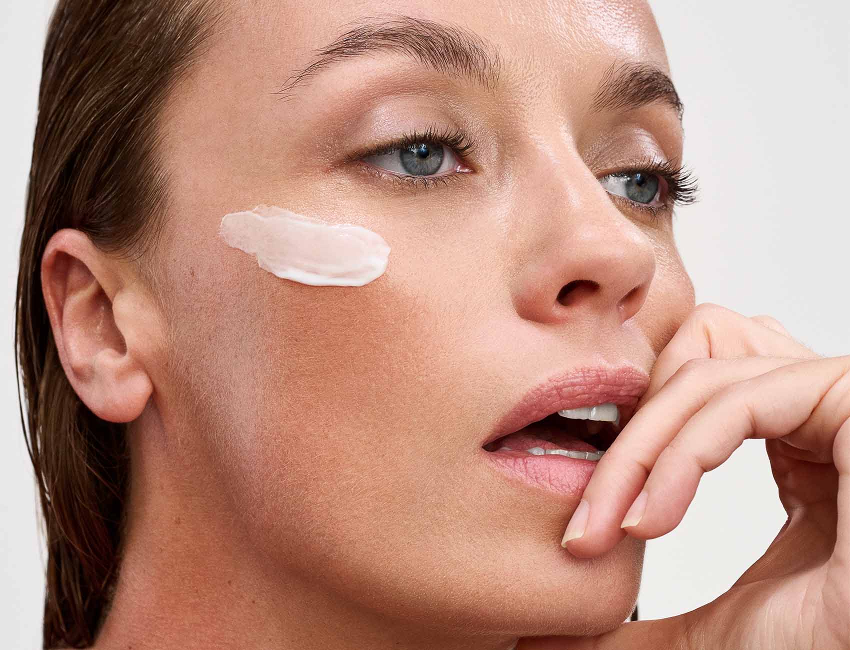 Close-up of a woman's face with a cosmetic product applied to her cheek.